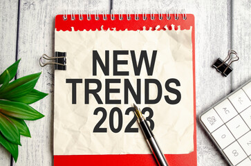 TRENDS 2023 text on paper with red notebook and pen with calculator