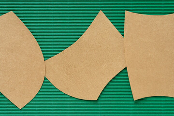 three gold paper shapes on green corrugated paper
