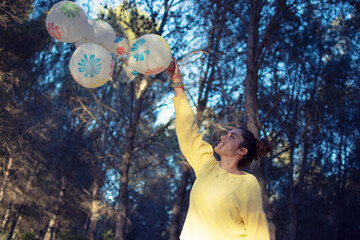 Pretty girl raising some balloons in the nature