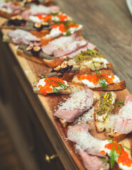 Catering table, beautifully decorated banquet table with variety of different food snacks, sandwiches, croissants and appetizers on a party event or celebration, delicatessen setting, coffee break