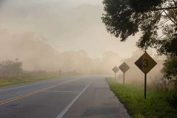 Empty highway in morning mist with warning signs on interior of Brazil