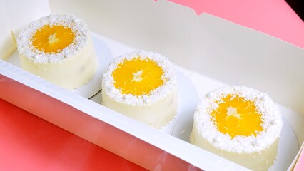Small cakes with orange and coconut shavings in a box.
