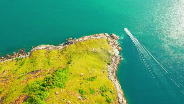 Aerial view over Krating cape, The viewpoint is a cliff area. There is a green grass and blue sea, Speed Boat is sailing on the sea. Phuket, Thailand. Amazing Nature Scenery. travel concept. 4K
