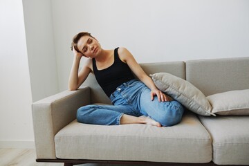 Young woman with short haircut hair having fun at home on the couch smile and happiness, vacation at home, natural posing without filters, free copy space