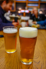 Fresh draught lager or IPA beer is glass served in indoor cafe close up, pint of beer