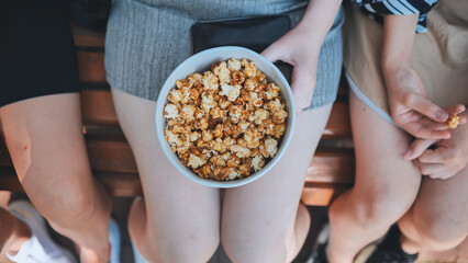 Friends eating popcorn on the street. Close-up of hands.