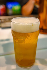 Fresh draught lager or IPA beer is glass served in indoor cafe close up, pint of beer