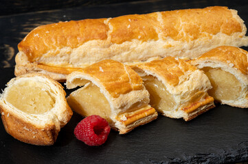 Fresh baked Dutch filled spicy cookies from puff pastry with almonds in autumn colors on dark stone