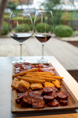 Wooden plate with sliced Spanish tapas, choriso sausage, lomo iberico en bread sticks served with glass of red wine
