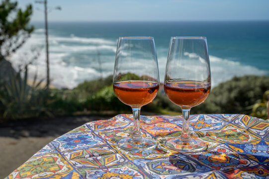 Tasting of sweet moscatel de setubal or porto portuguese wine and view on blue Atlantic ocean near Sintra in Lisbon area, Portugal