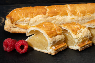Fresh baked Dutch filled spicy cookies from puff pastry with almonds in autumn colors on dark stone