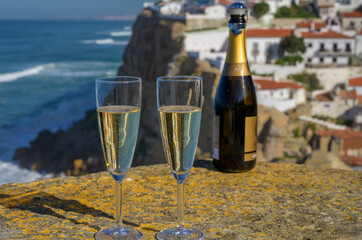 Glasses of champagne sparkling wine and view on white houses of picturesque village Azenhas do mar, Lisbon area, Portugal