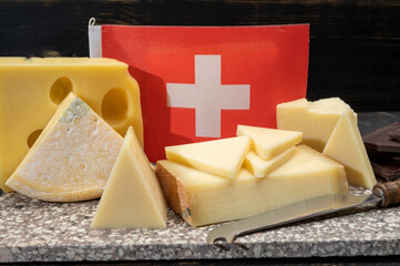 Assortment of Swiss cheeses Emmental or Emmentaler medium-hard cheese with round holes, Gruyere,...