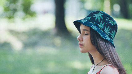 A teenage girl in a panama hat is walking through the park in the summer.