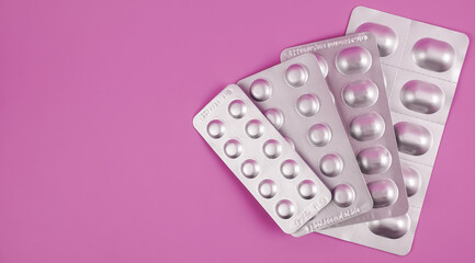 pile of tablets pill in silver blister packaging on pink background. Aluminium foil blister pack. Pharmacy products. Medicine pills and drugs close up. Pills background. - obrazy, fototapety, plakaty