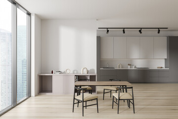 Light kitchen interior with table and cooking area with window. Mockup wall