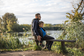 Father hugging his son outdoors on the bench. Precious moments between Dad  and son