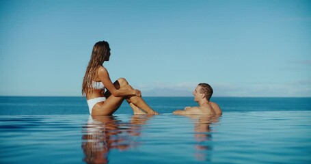 Attractive couple relaxing in luxury infinity pool at tropical resort spa, vacation honeymoon travel