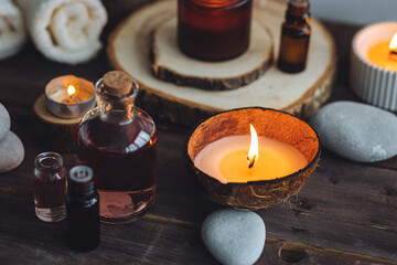 Concept of natural essential organic oils, Bali spa, beauty treatment, relax time. Atmosphere of relaxation, pleasure. Candles, towels, dark wooden background. Alternative oriental medicine