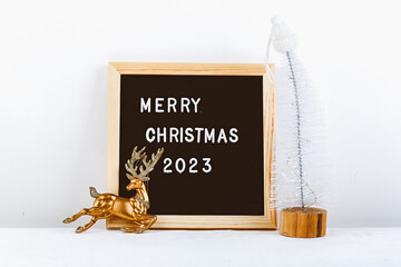 Merry Christmas lettering on letter board. Eco tree and golden deer. minimalistic new year background 2023
