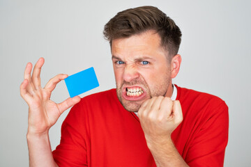 man feeling sad, upset or angry, frowning in disagreement with a credit card.