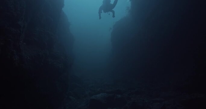 Scuba diver swims out through underwater cave.