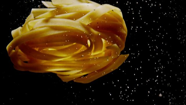 Slow motion close-up video of pasta being thrown into boiling water. The process of cooking Italian pasta in the kitchen. High quality 4k footage