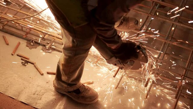 Industrial professional worker is cutting metal rebar with a circular saw. Construction of a factory, hangar