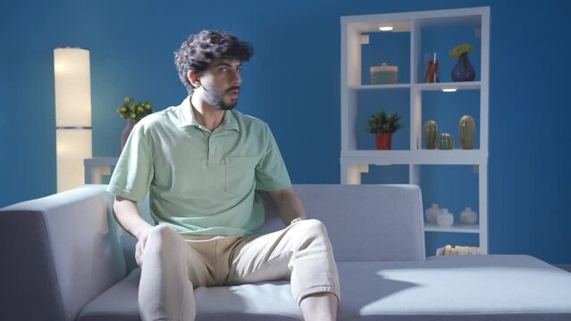Characterized by extreme anxiety and fear, the young man suffers alone at home.
Paranoid young man living with doubt and insecurity is afraid at home at night, not feeling well.
