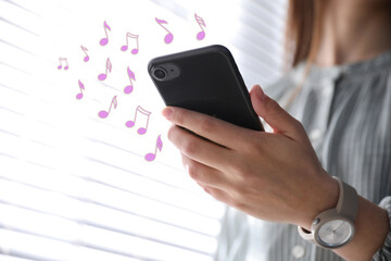 Woman listening to music on mobile phone indoors, closeup. Music notes illustrations near gadget