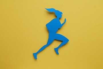Sportswoman paper figure on yellow background, top view. Woman`s health