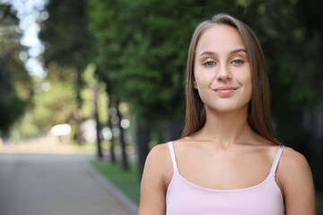 Portrait of beautiful young woman in park, space for text