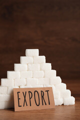 Card with word Export near pyramid of sugar cubes on wooden table, space for text