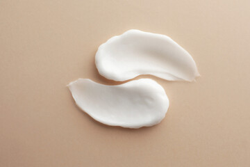Sample facial cream on beige background, top view