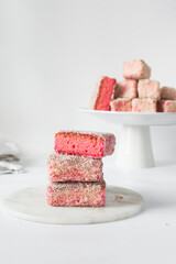 Pink lamingtons on a marble tray, Australian raspberry lamingtons, cake covered in desiccated coconuts