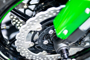 Motorcycle disc brake details next to Green motorcycle alloy wheels, use light effects