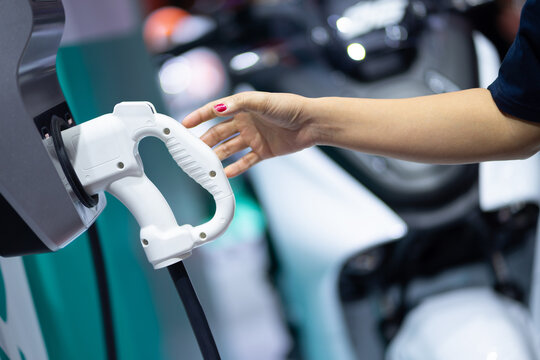 Female hand going to charge EV for electric vehicle in green energy and eco energy concept