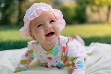 Smiling baby girl lay on the lawn in garden