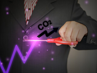 A businessman decides to use scissors to cut or eliminate the increase or rise of carbon dioxide in his business to maintain a level of the gas. Reduce CO2 emission concept.