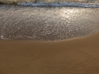 Pattern of waves on the sand with sunlight reflex