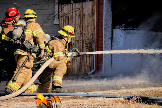 Firefighter uses a hose to battle a house fire