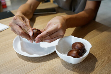 Man's hand peeling a tea infused egg at a tea house in Kuala Lumpur, Malaysia                               