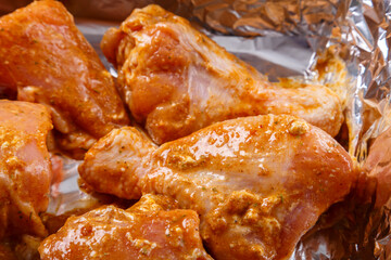 chicken parts in soy sauce and spicy spices marinated on foil.