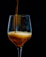 Pouring dark beer into a glass isolated on a black background.
