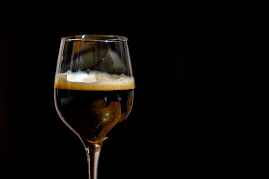 Dark beer in a glass on a black background.