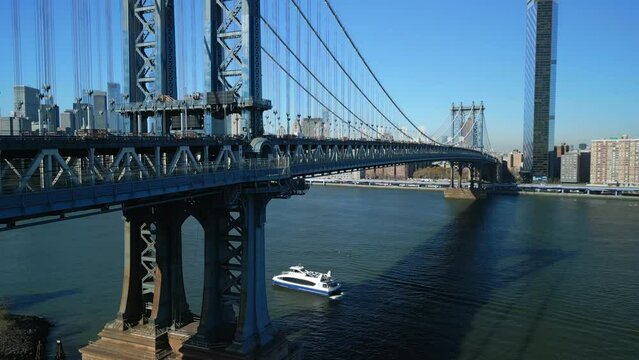 Slide and pan footage of double deck steel bridge over river. Manhattan skyscrapers in background. New York City, USA