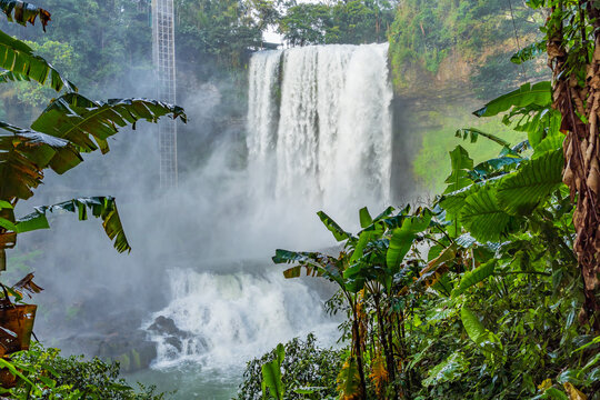 A tall waterfall falling down two tiers in a jungle setting at Dambri Falls in Vietnam