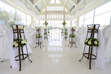 Christ Church decorated in bright white tones. for celebrating the wedding ceremony There was a crucifix in the center of the room and many chair flowers.