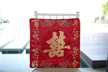 1 red pillow for the red Chinese wedding ceremony There are auspicious characters and dragon patterns written on the pillow. sits on a chair.