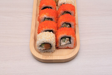 Delicious Japanese rolls with salmon, avocado, cucumber, cheese on wooden plate with selective focus. Asian food concept. Healthy eating